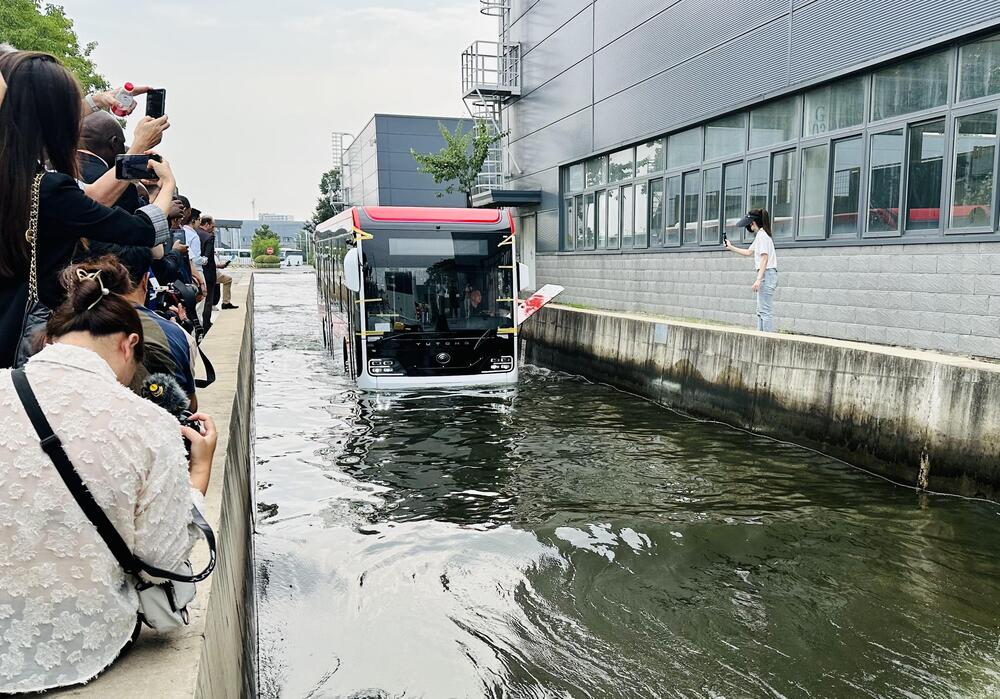 Members of the delegation take pictures of an electric bus produced by Yutong Bus during a wading test at the manufacturing base of the company. (China Daily) Members of the delegation take pictures of an electric bus produced by Yutong Bus during a wading test at the manufacturing base of the company. (China Daily)