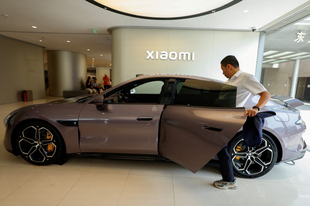 A person tries the electric sedan SU7 displayed at a Xiaomi store in Beijing, China May 29, 2025. REUTERS/Tingshu Wang/File Photo