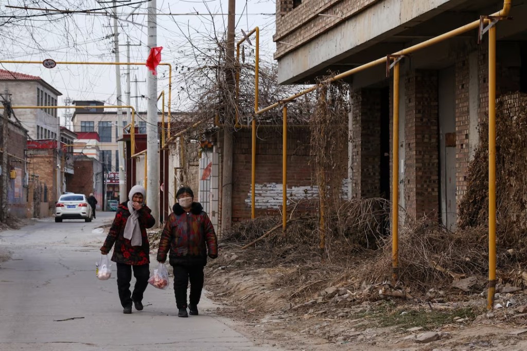 Villagers walk past natural gas pipes at a village in Baoding, Hebei province, China January 13, 2026. REUTERS/Tingshu Wang 