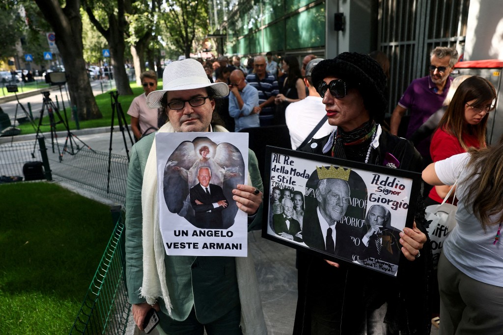 People holding placards queue outside the Armani/Teatro to pay tribute as designer Giorgio Armani lies in state, following his death at the age of 91, in Milan, Italy September 7, 2025. (Reuters)