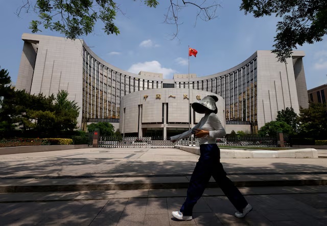 A person walks past the headquarters of the People's Bank of China, in Beijing, China May 7, 2025. REUTERS/Tingshu Wang