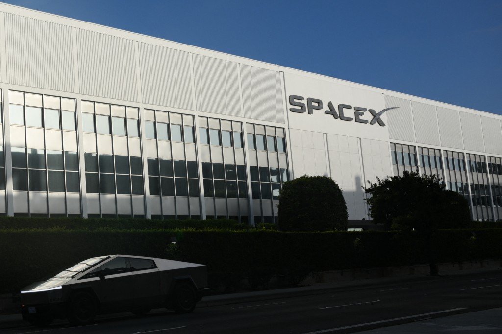 The SpaceX logo is seen on a building as a Tesla Cybertruck drives past a Space Exploration Technologies Corp. facility in Hawthorne, California, on June 9, 2026. (Photo by Patrick T. Fallon / AFP)