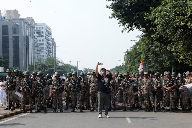 A man takes selfie with security personnel as opposition parties march to the Supreme Court in protest against a controversial revision of voter lists that has sparked days of unrest, in New Delhi, India, October 12, 2026. REUTERS/Bhawika Chhabra