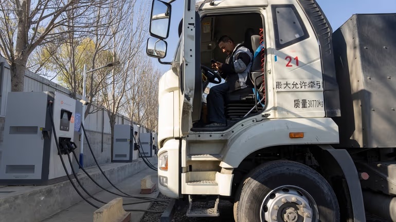 A driver sits in his electric truck at a charging station on the outskirts of Beijing, on Nov. 14, 2025. Credit: AP/Ng Han Guan