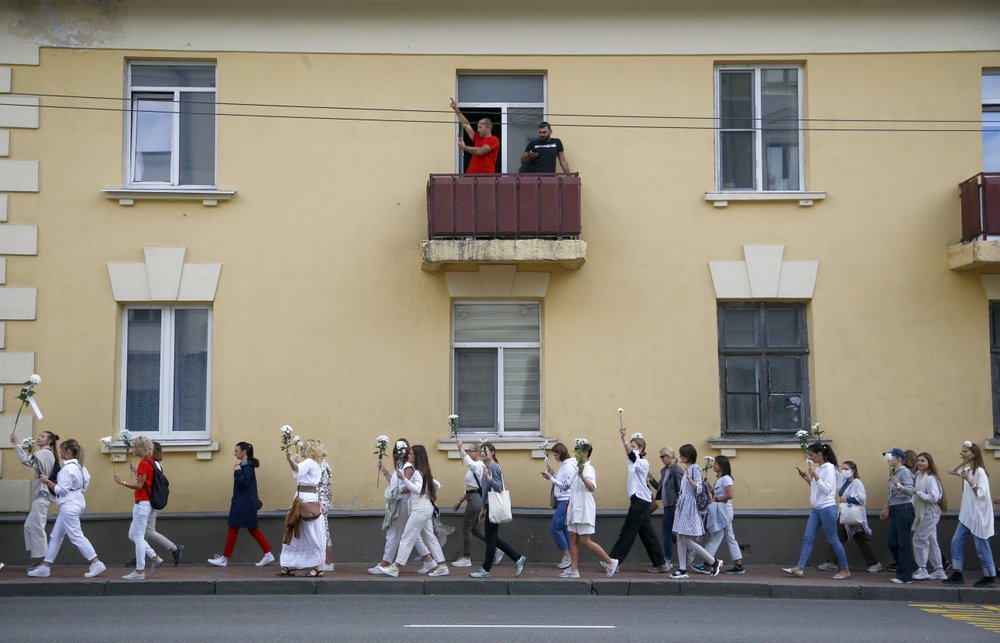 Belarusian women rally in solidarity with protesters injured in the latest rallies against the results of the country's presidential election while two men on a balcony greet them in Minsk, Belarus