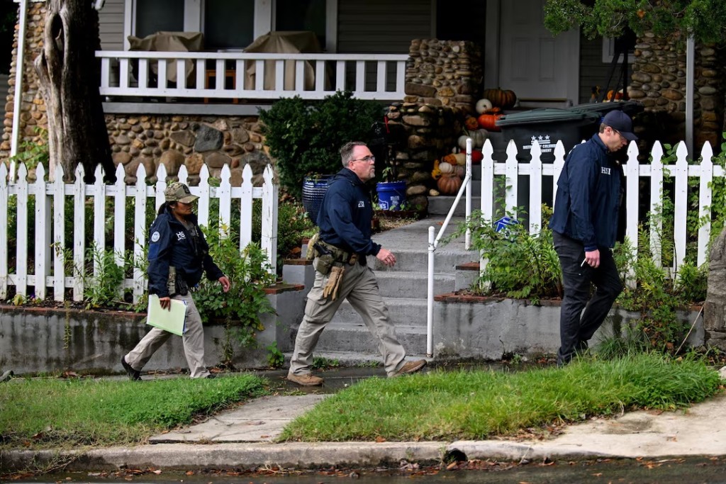 Agents of the Homeland Security Investigations (HSI) walk in the neighborhood where US Rep. Ilhan Omar (D-MN) resides, after US authorities conducted a raid as part of an ongoing investigation by the Justice Department, in Washington, DC, US, October 12, 2026. REUTERS/Annabelle Gordon. 