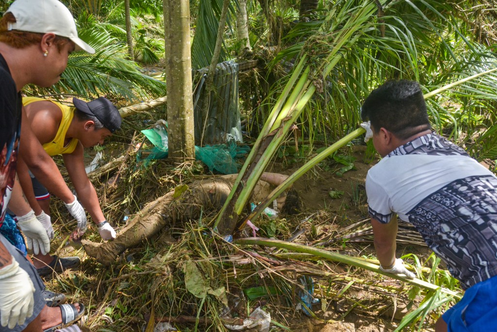 Photo by ALAN TANGCAWAN / AFP  Graphic content / Volunteers retrieve a dead body swept away among the trees in the aftermath of Typhoon Kalmaegi in Liloan town, Cebu province, central Philippines on November 5, 2025.