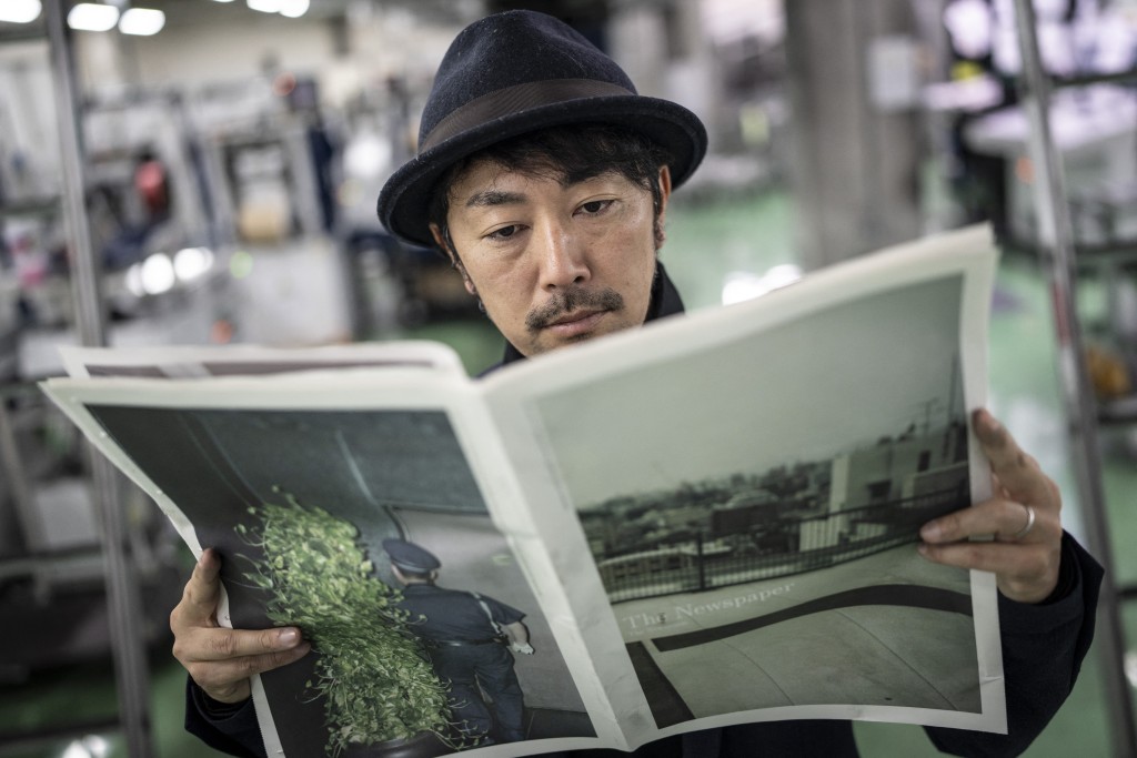 Photo by YUICHI YAMAZAKI / AFP  This picture taken on March 19, 2026 shows photographer Kazuma Obara posing with his work titled “The Newspaper” at the Kyoto Shimbun factory in Kumiyama, Kyoto prefecture.