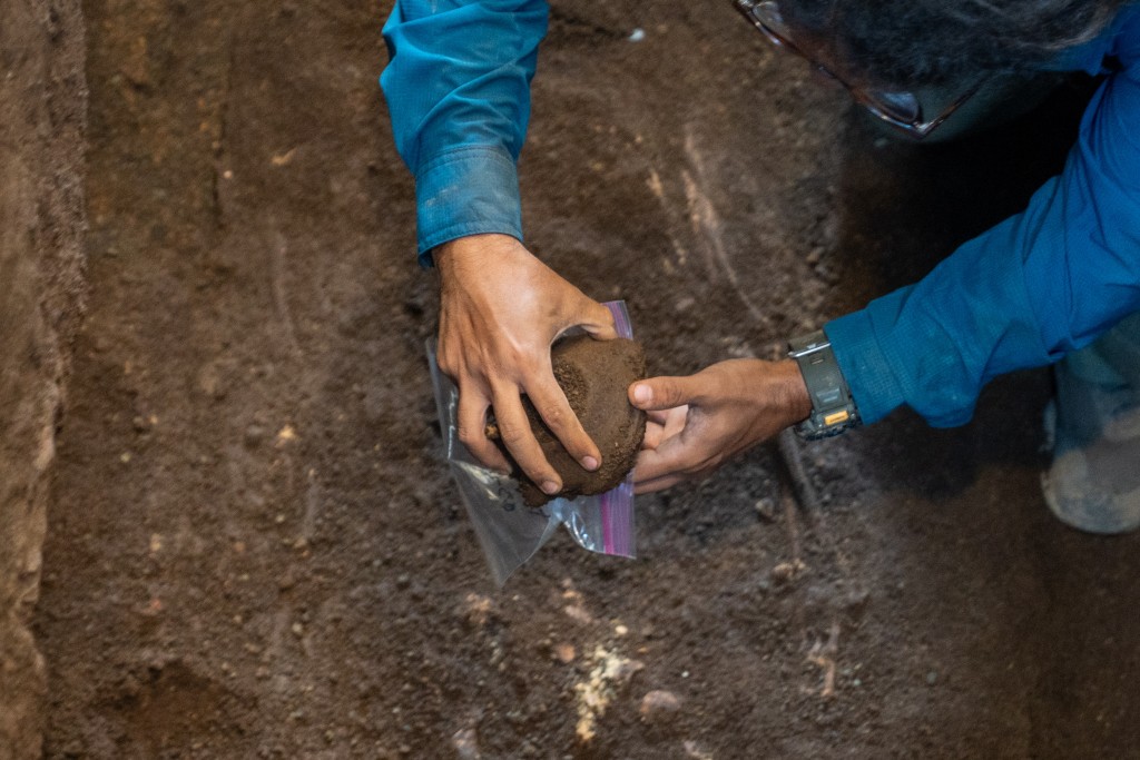 Photo by HANDOUT / EL SALVADOR'S PRESIDENCY PRESS OFFICE / AFP  This handout image released by El Salvador's Presidency shows an archaeologist handling a ceramic vessel recovered from a pre-Hispanic burial estimated to date to 850 B.C. at an archaeological site in Antiguo Cuscatlan, El Salvador, on July 21, 2026.