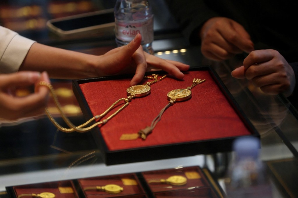 A staff member attends to a customer at a Laopu Gold jewellery store in Beijing, China March 12, 2025. REUTERS