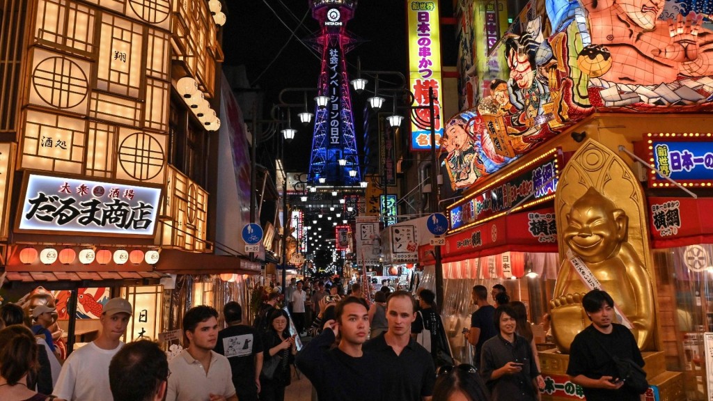 Tourists frolic the popular Shinsekai area in Naniwa ward as Tsutenkaku Tower looms in the background in Osaka. AFP