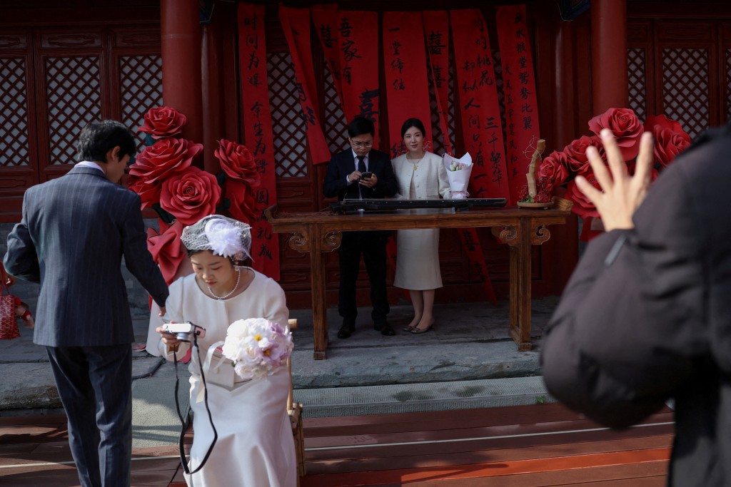Newlywed couples pose for pictures at the Huguo Guanyin Temple, an outdoor marriage registration site in Beijing. (Reuters)