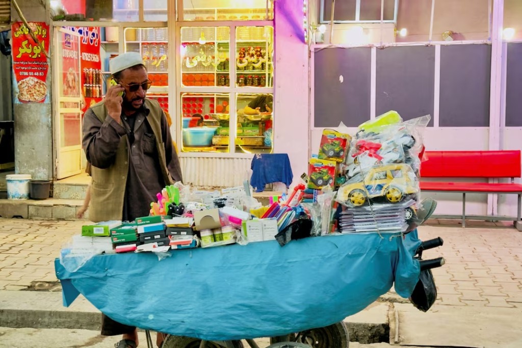 An Afghan street vendor speaks on his phone after telecom and internet services resumed in Kabul, Afghanistan, October 1, 2025. REUTERS/Sayed Hassib