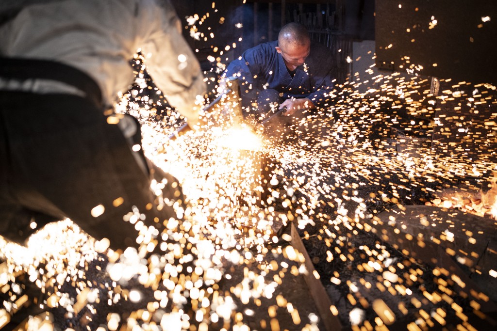 Photo by YUICHI YAMAZAKI / AFP  This picture taken on January 9, 2026 shows sparks flying as swordsmith Akihira Kawasaki (R) steadies steel over an anvil while his apprentice Toru Watanabe hammers the metal to forge katana blades at Kawasaki's workshop in Misato, Saitama prefecture.