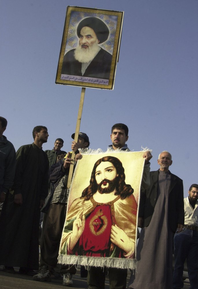 In this Janaury 19, 2004 file photo, an Iraqi Christian holds a carpet with an image of Jesus Christ and a poster of Grand Ayatollah Ali al-Husseini al-Sistani during a march in Baghdad, Iraq. In this Janaury 19, 2004 file photo, an Iraqi Christian holds a carpet with an image of Jesus Christ and a poster of Grand Ayatollah Ali al-Husseini al-Sistani during a march in Baghdad, Iraq.