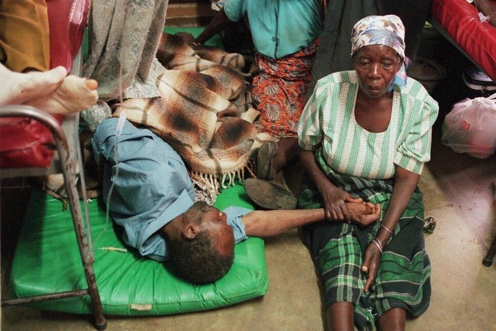 FILE - A woman holds the hand of a sick relative lying on the floor of the overcrowded Lilongwe Central Hospital, in Lilongwe, Malawi, Sept. 30, 1998, as the hospital is overflowing because of an epidemic of AIDS rampaging in southern Africa. (AP Photo /Denis Farrell, File) FILE - A woman holds the hand of a sick relative lying on the floor of the overcrowded Lilongwe Central Hospital, in Lilongwe, Malawi, Sept. 30, 1998, as the hospital is overflowing because of an epidemic of AIDS rampaging in southern Africa. (AP Photo /Denis Farrell, File)