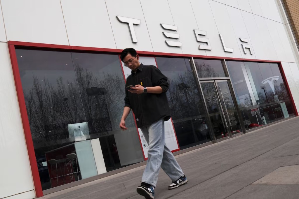 A man walks by at a store of the electric vehicle (EV) maker Tesla, in Beijing, China March 24, 2025. REUTERS