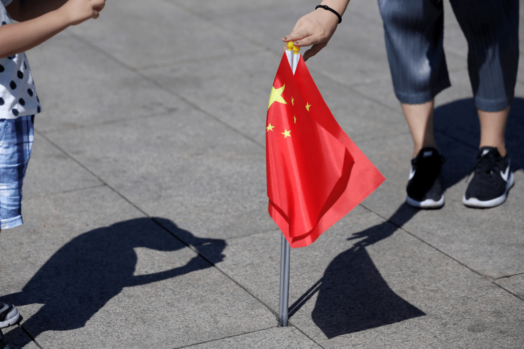 A mother holds Chinese flags as she helps her son take a picture on Tiananmen Square, in Beijing, China August 27, 2019. REUTERS/Jason Lee 