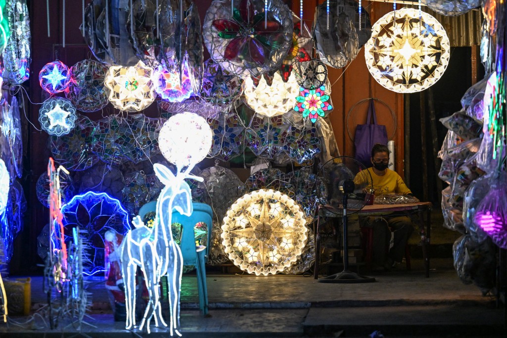 Photo by JAM STA ROSA / AFP  This photo taken on December 4, 2025, shows a woman working on a lantern as she waits for customers in San Fernando, Pampanga.