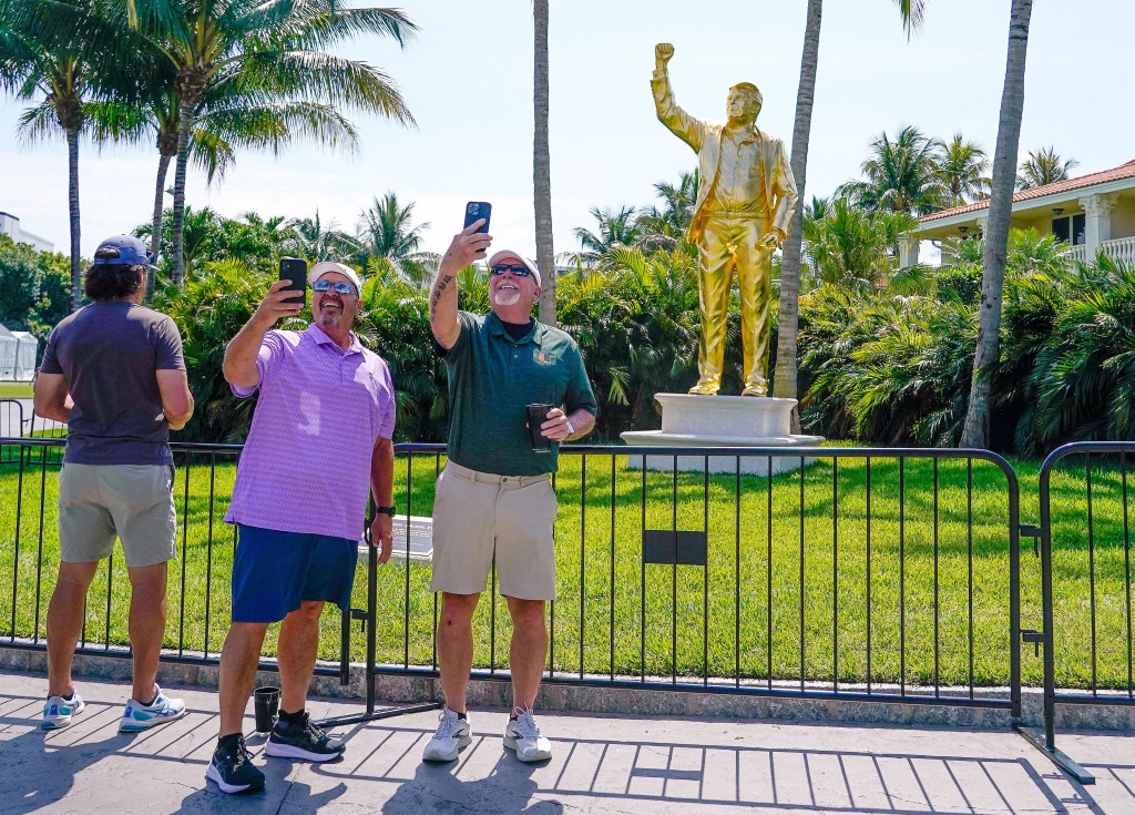 Apr 30, 2026; Miami, Florida, USA; Fans pose for a photo in front of a statue of President Donald Trump during the first round of the Cadillac Championship golf tournament. Mandatory Credit: Jeff Romance-Imagn Images - Reuters