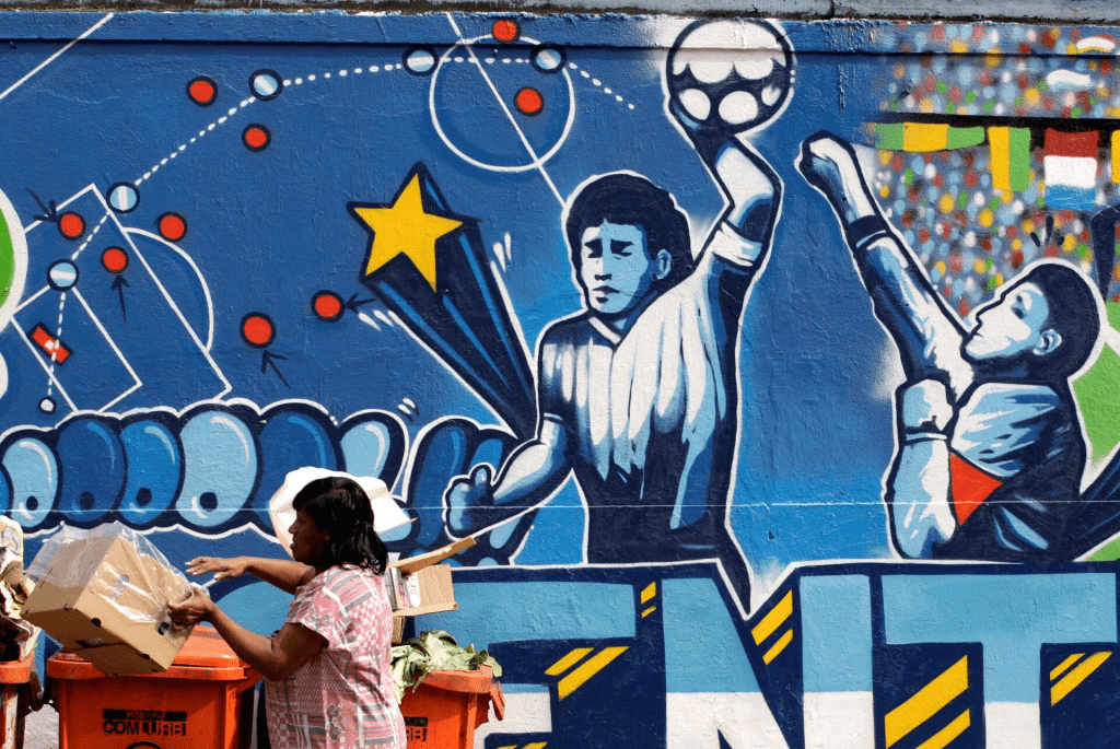 A resident stands near a mural depicting the famous "Hand of God" goal by former Argentine soccer star Diego Maradona, in light of the upcoming 2010 FIFA World Cup at the Agua Santa neighborhood in Rio de Janeiro May 21, 2010. REUTERS/Sergio Moraes/