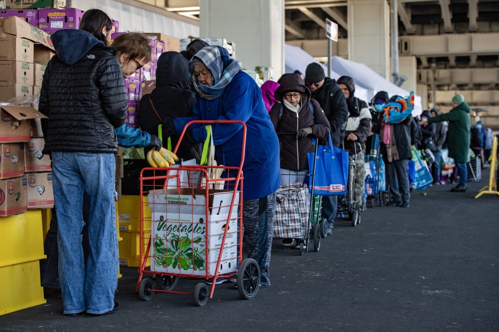 Photo by JOSEPH PREZIOSO / AFP  Workers and volunteers hand out food to people in line at La Colaborativa's food pantry in Chelsea, Massachusetts, on November 15, 2025.