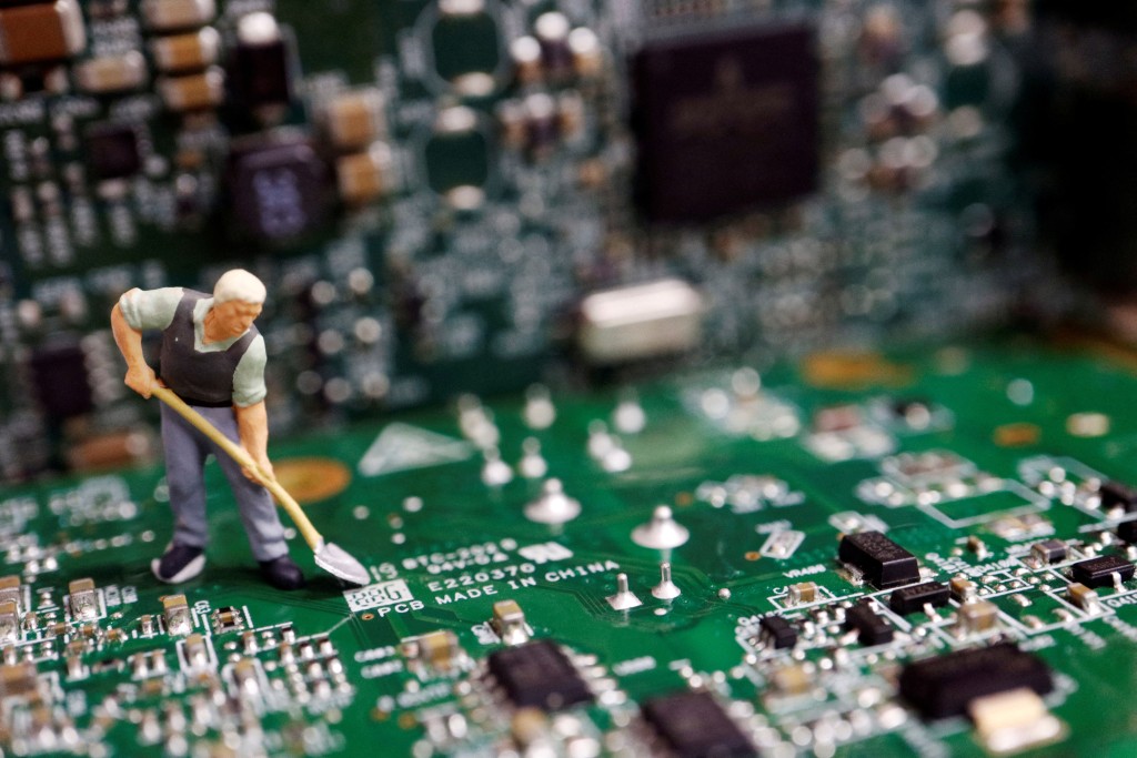 A worker miniature is placed among printed circuit boards with semiconductor chips, in this illustration picture taken July 5, 2023. REUTERS