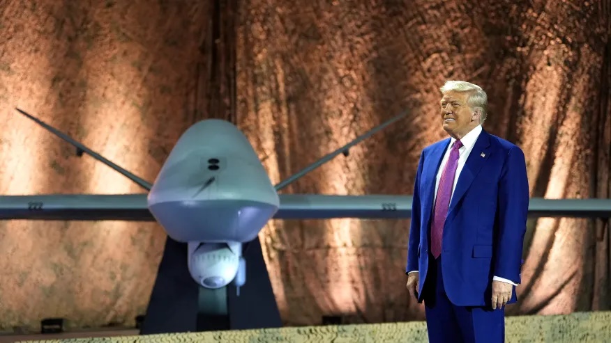 President Donald Trump stands backdropped by an MQ-9 Reaper drone before addressing military personnel at the Al Udeid Air Base, Thursday, May 15, 2025, in Doha, Qatar. (AP Photo/Alex Brandon)