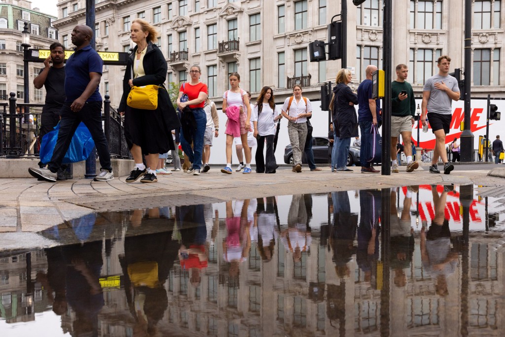 People and shoppers are reflected in a puddle on Oxford Circus in London, Britain July 31, 2025. REUTERS/Jack Taylor
