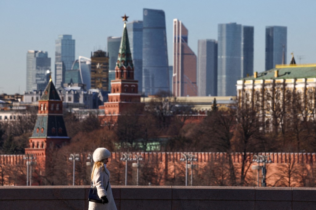 A woman walks along a bridge, with the Moscow City business centre and the Kremlin wall seen in the background, on a sunny day in Moscow, Russia, February 24, 2025. REUTERS/Evgenia Novozhenina//File Photo