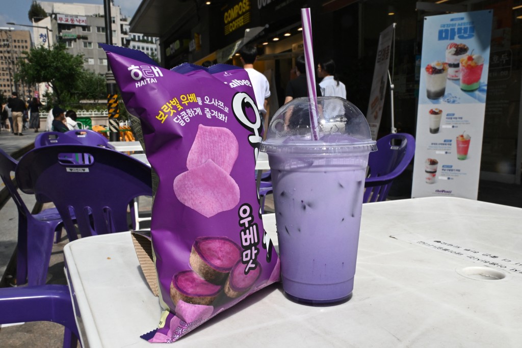 Photo by JUNG YEON-JE / AFP  This illustration photo taken on September 23, 2026 shows a cup of iced ube latte and a bag of ube-flavored snacks placed on a table at a walk-up cafe in Seoul.