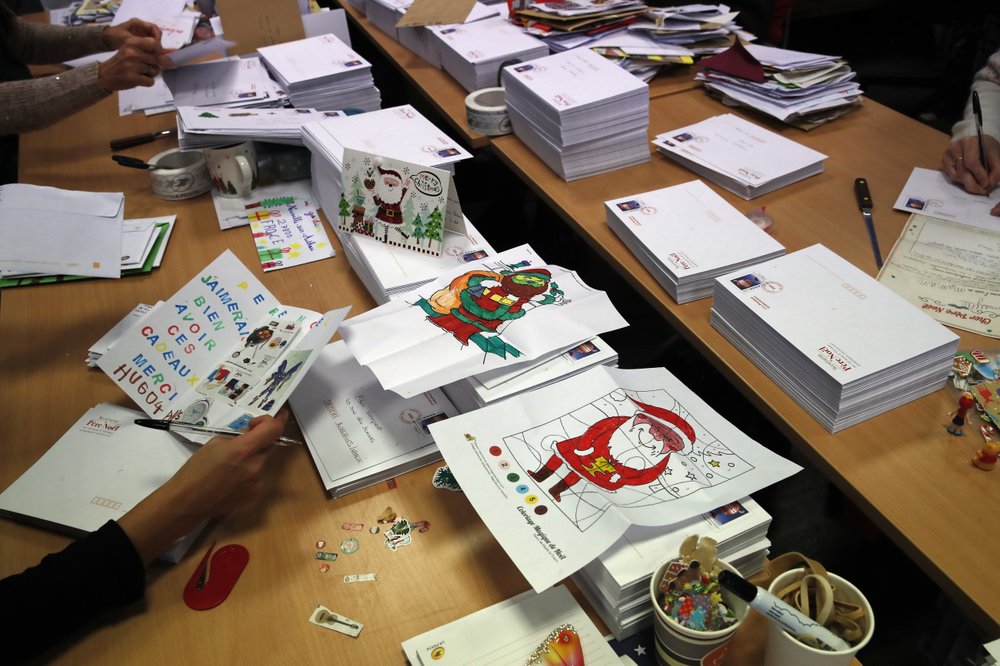 Postal workers who call themselves 'Elves' open envelopes addressed to 'Pere Noel' - Father Christmas in French - decorated with love hearts, stickers and glitter, in Libourne, southwest France, Monday, November 23.