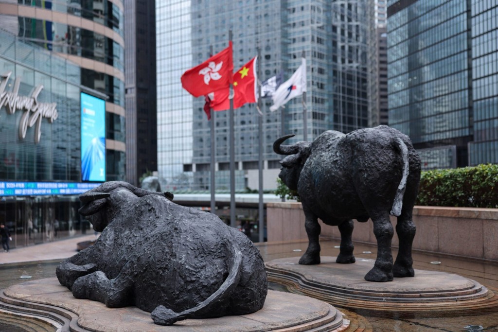 Bull statues near screens showing the Hang Seng stock index and stock prices outside Exchange Square, in Hong Kong, China, February 3, 2026. REUTERS