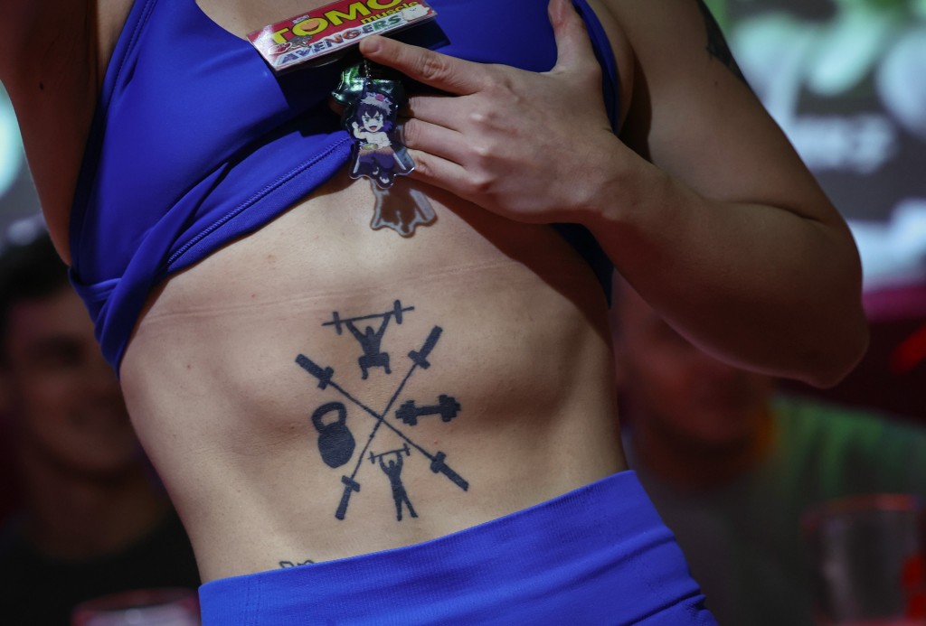 Tomomi Matsumoto, 35, a staffer at Muscle Girls, a fitness-themed bar, lifts her shirt to show customers a tattoo on her torso in Tokyo, Japan, September 11, 2025. REUTERS/Kim Kyung-Hoon