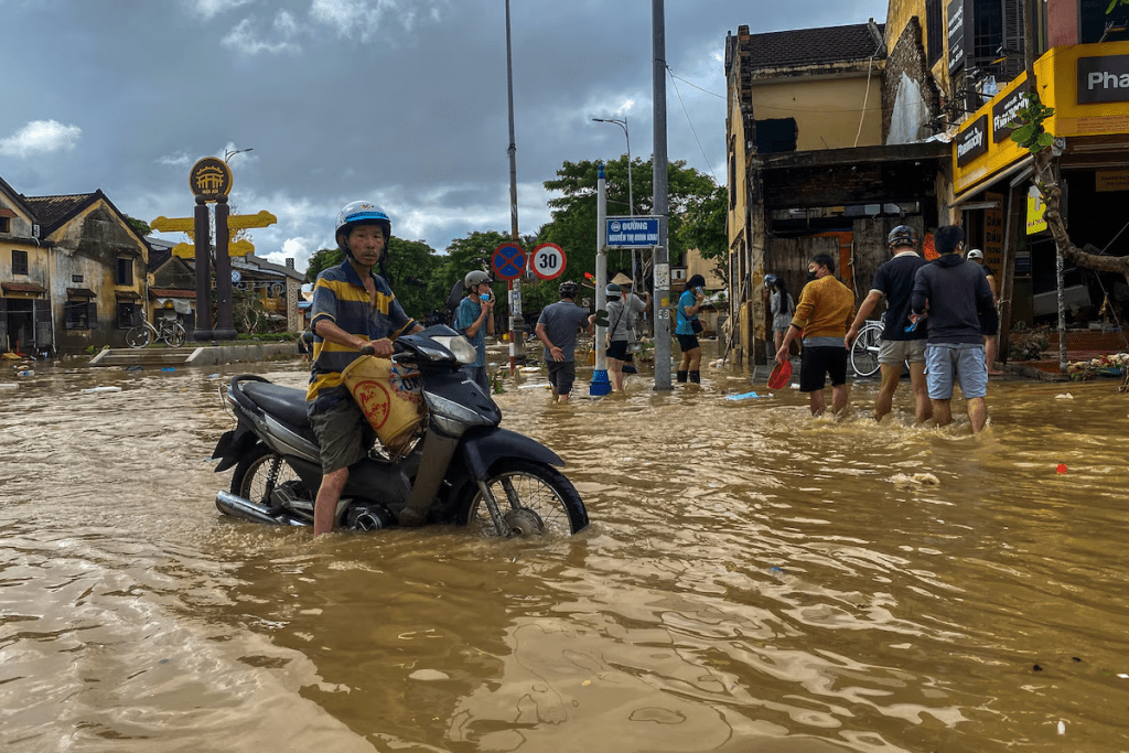 People wade through a flooded street, as a motorist looks on, in Hoi An, following deadly floods in central Vietnam, October 31, 2025. REUTERS/Thinh Nguyen