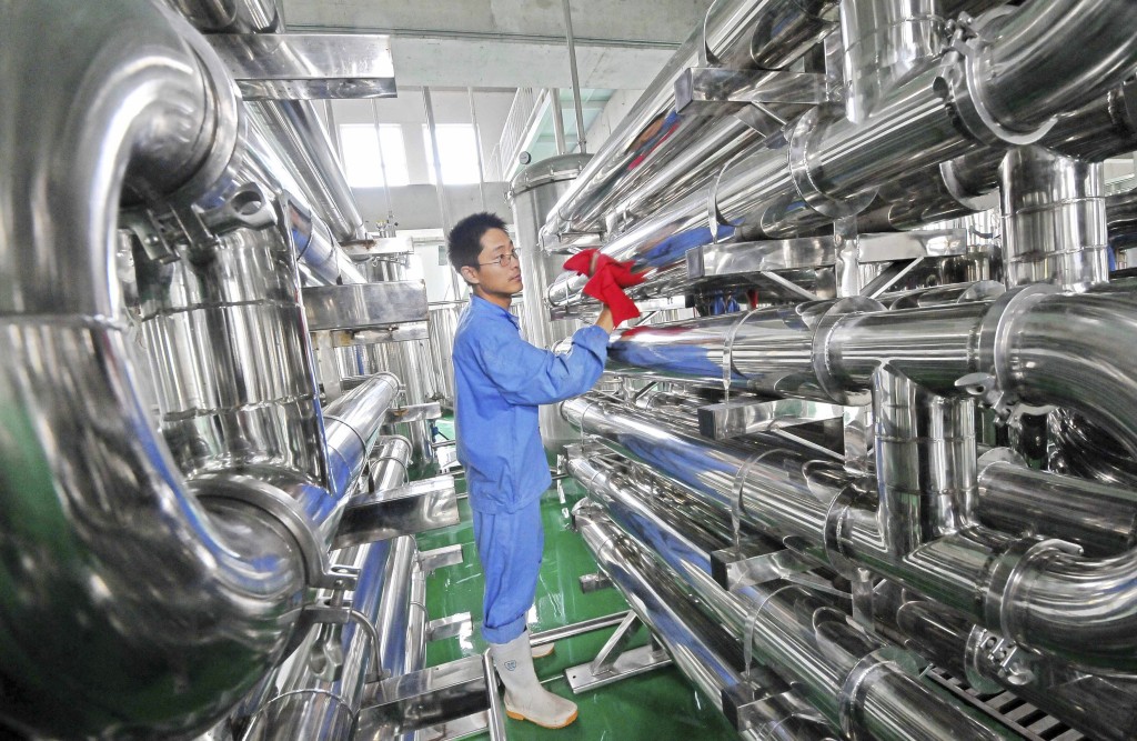 An employee wipes equipment on the production line of hawthorn red wine at a factory in Weifang, Shandong province July 28, 2013. Reuters