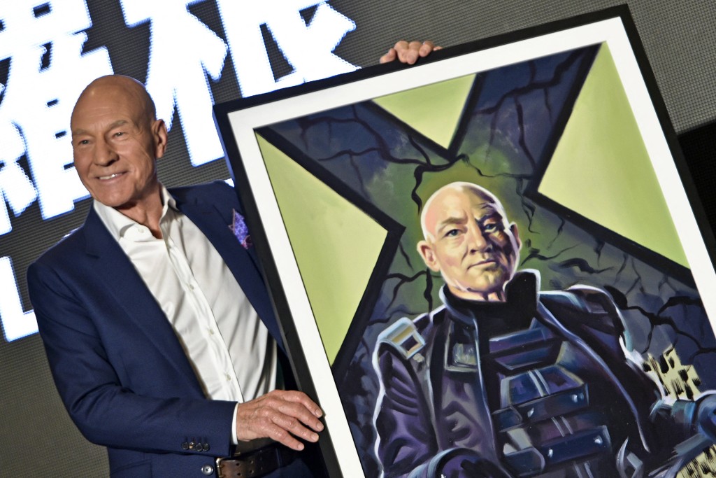 Photo by SAM YEH / AFP  "Professor X" in the X-Men series' Patrick Stewart poses for photos with a gift of a painting during a press conference for the film "Logan" in Taipei on February 28, 2017.