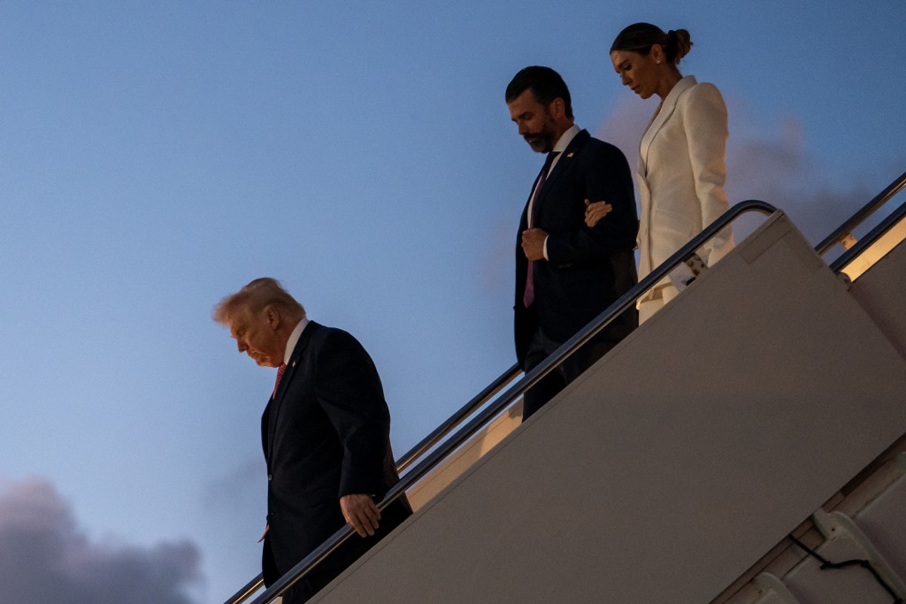 U.S. President Donald Trump exits Air Force One along with his son Donald Trump Jr. and Bettina Anderson while arriving at Palm Beach International Airport on March 27, 2026 in West Palm Beach, Florida. President Trump will spend the weekend at his Mar-a-Lago resort in Florida. Nathan Howard/Getty Images/AFP