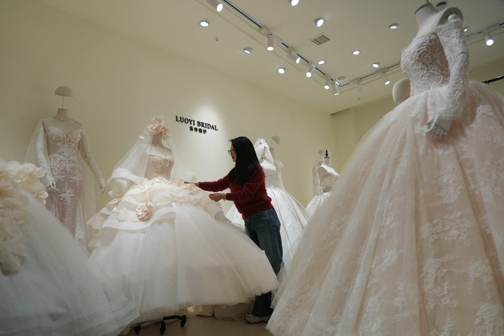 Chen Juan, co-owner of wedding dress shop Luoyi Bridal, adjusts a gown on display at the shop in Huqiu Bridal City in Suzhou, Jiangsu province, China January 16, 2026. (Reuters)