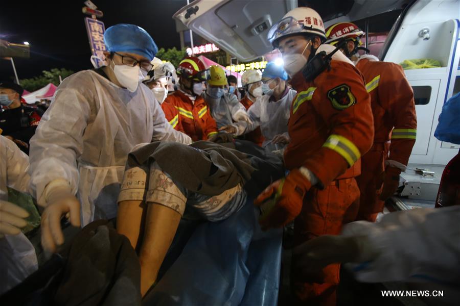 Rescuers transfer a woman to an ambulance at the accident site of a quarantine hotel building collapse in Quanzhou, southeastern Fujian province, yesterday. Rescuers transfer a woman to an ambulance at the accident site of a quarantine hotel building collapse in Quanzhou, southeastern Fujian province, yesterday.