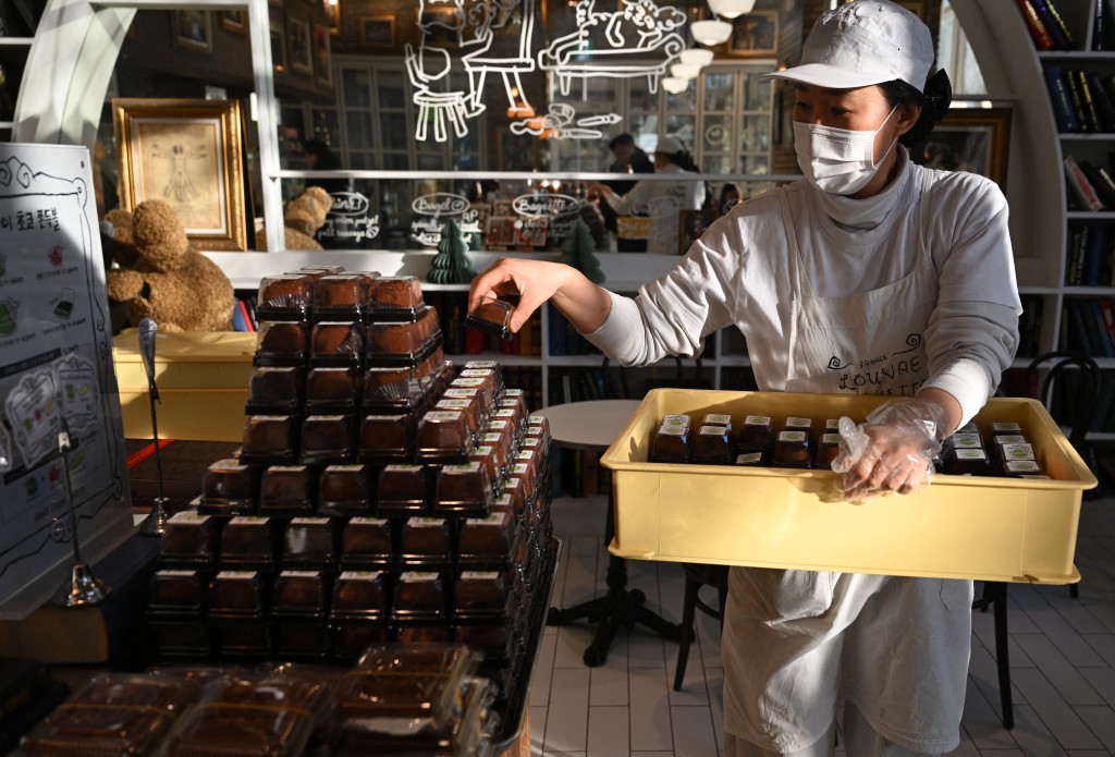 Photo by JUNG YEON-JE / AFP  An employee displays "Dubai-style" chewy chocolate cookies at a bakery cafe in Seoul on January 20, 2026.