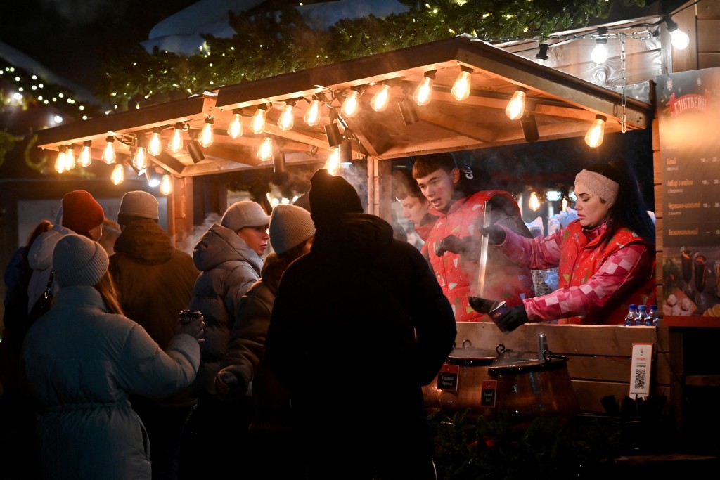 Visiters queue to drink hot mulled wine at a stand of the Christmas Fair at the Ukrainian National Exhibition Center in Kyiv on December 21, 2025, amid the Russian invasion in Ukraine. (Photo by Sergei SUPINSKY / AFP)