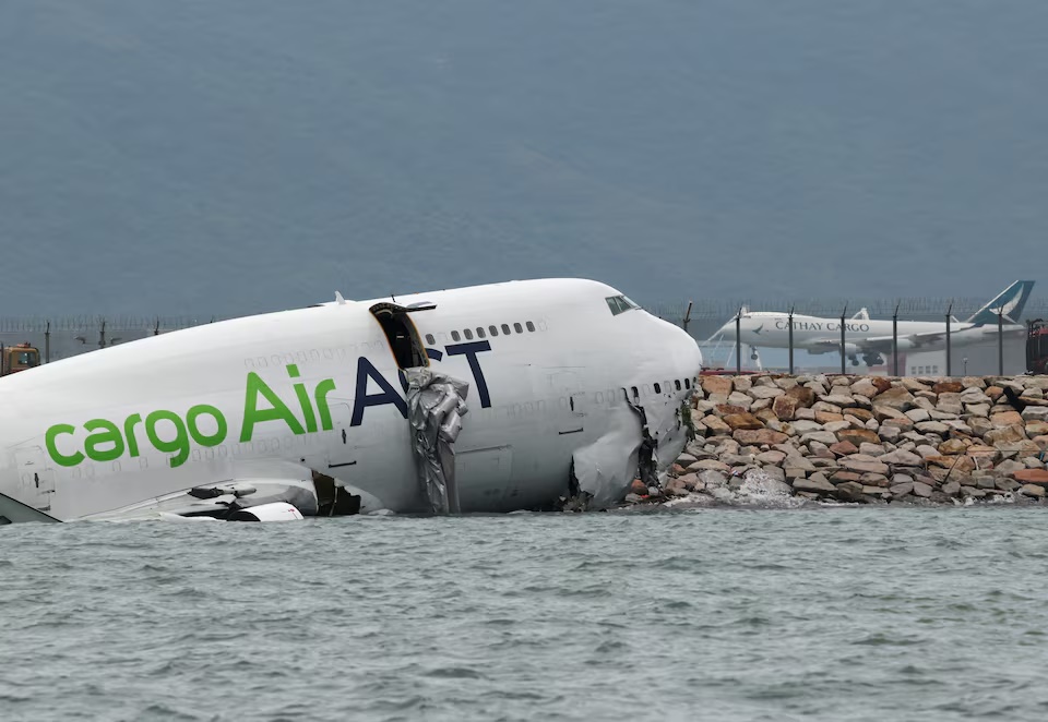 A cargo plane lies partially in the sea after veering off the runway during landing at Hong Kong International Airport in Hong Kong, China, October 20, 2025. REUTERS/Tyrone Siu
