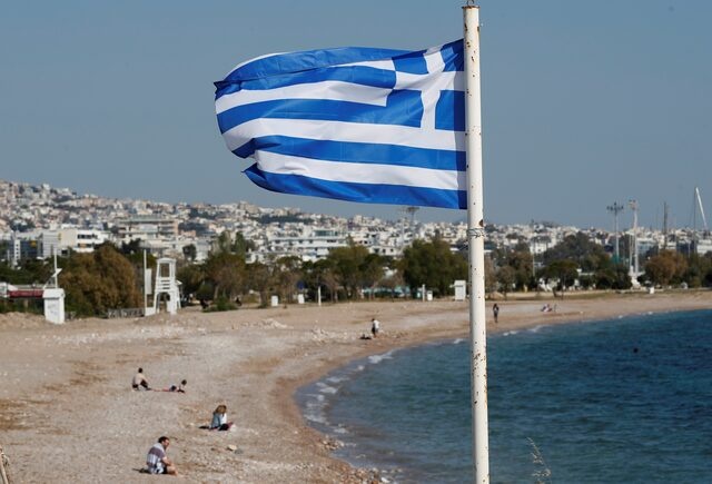 A Greek national flag flutters as people visit a beach, following the coronavirus disease (COVID-19) outbreak, in Athens, Greece, April 28, 2020. REUTERS/Goran Tomasevic