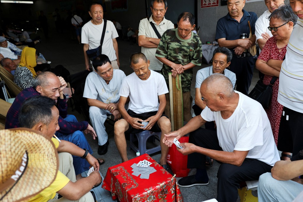 People play cards at the entrance of a hallway of an air-conditioned metro station amid a red alert for heat in Chongqing, China July 31, 2025. REUTERS/Go Nakamura
