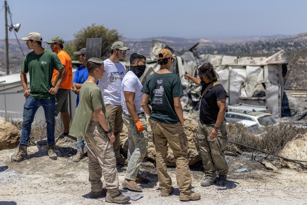 Israeli settlers inspect the aftermath of a fire that broke out the previous day in the Israeli settlement of Havat Gilad, adjacent to the Palestinian village of Tell in the occupied West Bank, on July 19, 2026. Multiple fires broke out in the north of the West Bank on July 18, forcing the evacuation of the Havat Gilad settlement and injuring at least two firefighters, according to police and rescuers.