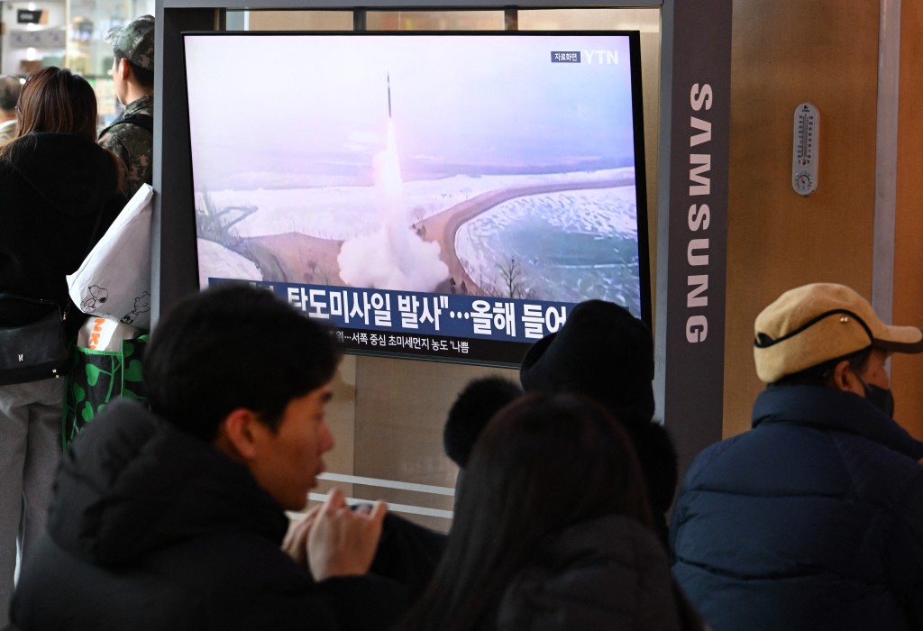 People sit in front of a television screen showing a news broadcast with file footage of a North Korean missile test, at a train station in Seoul on January 4, 2026. (AFP)