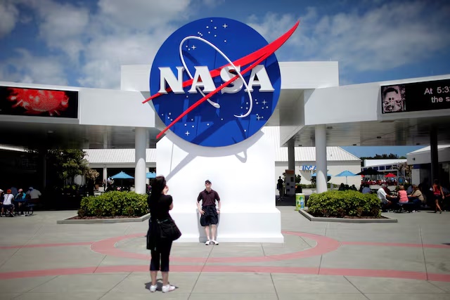 Tourists take pictures of a NASA sign at the Kennedy Space Center visitors complex in Cape Canaveral, Florida April 14, 2010. REUTERS/Carlos Barria/File Photo 