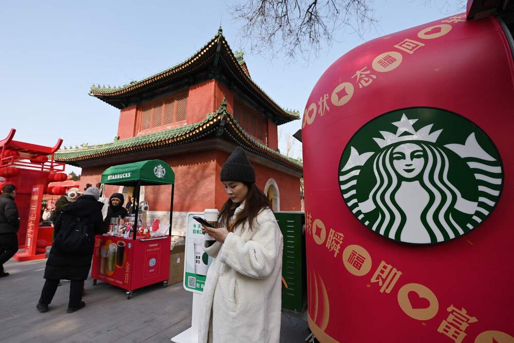 People wait to get coffee at a mobile Starbucks set up next to a historic building at a temple fair on the second day of the Lunar New Year of the Snake in Beijing on January 30, 2025. AFP