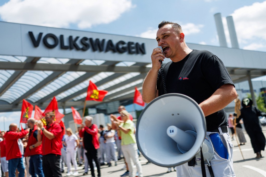 A participant with a megaphone addresses employees of German car maker Volkswagen (VW) during a rally called by German trade union IG Metall to protest against restructuring and mass job cut plans at the VW plant in Zwickau, eastern Germany on July 9, 2026. AFP